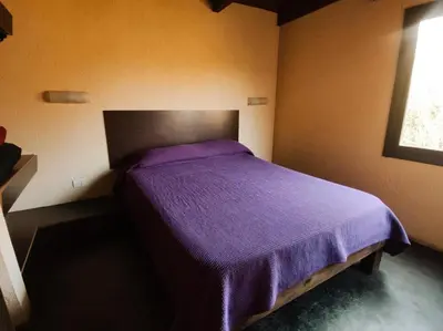 a bedroom with a purple bed with a window at Cabañas De La Vertiente in La Bolsa