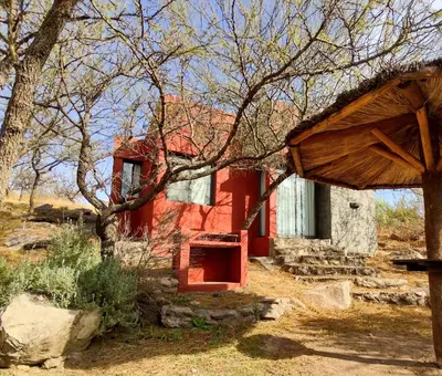 an old red house in the middle of a field at Cabañas De La Vertiente in La Bolsa