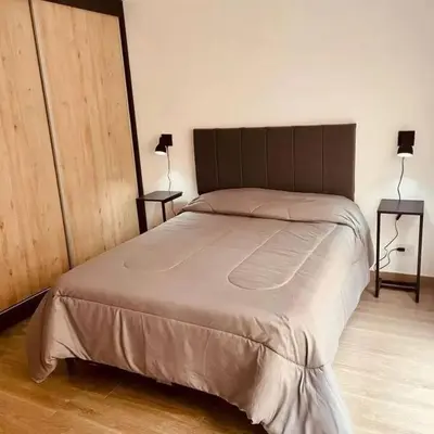 a bed in a bedroom with two lamps and two tables at Depto Villa Carlos Paz in Villa Carlos Paz