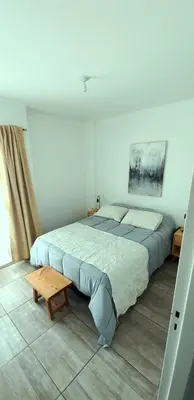 a bedroom with a large bed and a wooden table at Departamento Rivera in Cordoba