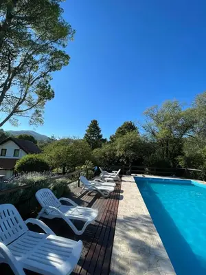 a row of white chairs next to a swimming pool at Complejo Villa General Belgrano in Villa General Belgrano