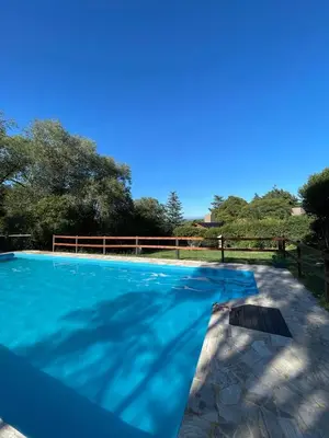 a swimming pool with blue water and a fence at Complejo Villa General Belgrano in Villa General Belgrano