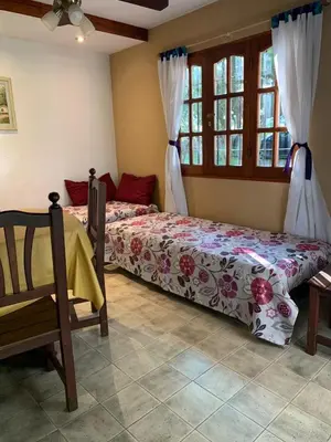 a bedroom with two beds and a chair and windows at Complejo Villa General Belgrano in Villa General Belgrano