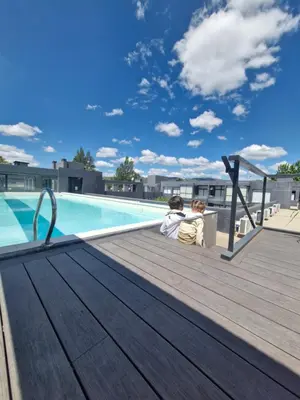 a couple sitting on a deck next to a swimming pool at Departamento VCP Costanera in Villa Carlos Paz