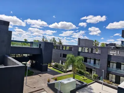 an apartment building with a courtyard with palm trees at Departamento VCP Costanera in Villa Carlos Paz