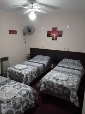 a room with two beds and a ceiling fan at Hotel Las Vegas in Villa Carlos Paz