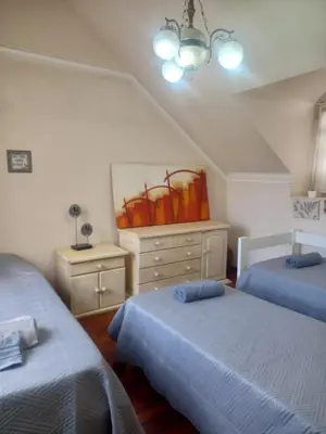 a bedroom with two beds and a dresser and a painting at Casa en el cerro de las Rosas con pileta in Cordoba