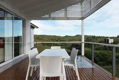 a white table and chairs on a balcony with a view at Dique Los Molinos Exclusiva casa vista al lago in Cordoba