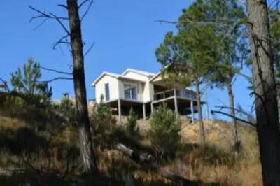 a white house on top of a hill with trees at Dique Los Molinos Exclusiva casa vista al lago in Cordoba