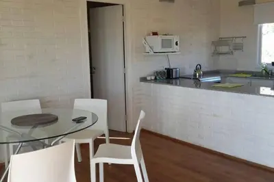a kitchen with a glass table and white chairs at Dique Los Molinos Exclusiva casa vista al lago in Cordoba