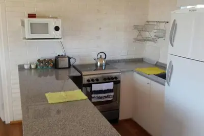 a kitchen with a stove and a white refrigerator at Dique Los Molinos Exclusiva casa vista al lago in Cordoba