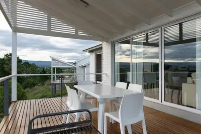 a porch with a white table and chairs on a deck at Dique Los Molinos Exclusiva casa vista al lago in Cordoba