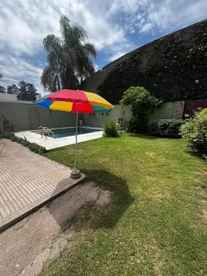 a colorful umbrella in a yard next to a pool at Apart Pilar in Pilar