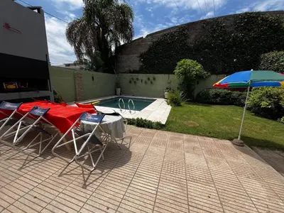 a table and chairs with an umbrella next to a pool at Apart Pilar in Pilar