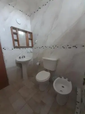 a white bathroom with a toilet and a sink at CapFer Alojamiento in Alta Gracia