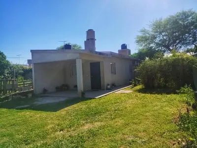 a small white house with a grass yard at CapFer Alojamiento in Alta Gracia
