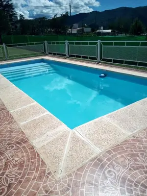 a swimming pool with blue water on a tennis court at Cabaña Alma Serrana in Bialet Massé