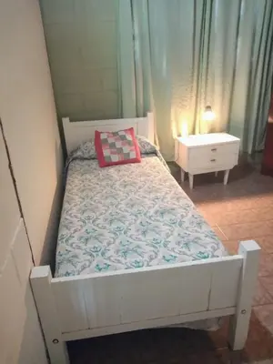a white bed with a red pillow and a night stand at Cabaña Alma Serrana in Bialet Massé