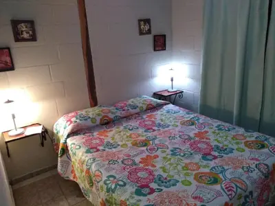 a bedroom with a bed with a floral bedspread and two lamps at Cabaña Alma Serrana in Bialet Massé