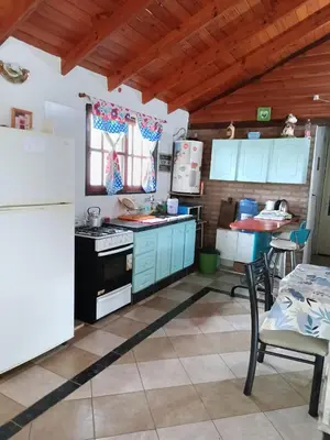 a kitchen with blue cabinets and a table and a refrigerator at Cabaña Alma Serrana in Bialet Massé