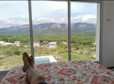 a person laying on a bed looking out a window at Traslavista alojamiento de ensueño in Villa de Las Rosas