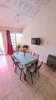 a dining room with a table with chairs and a television at Alojamiento El Caracol in Villa Carlos Paz