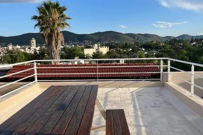 a bench on the roof of a building with a palm tree at Departamento en Villa Carlos Paz in Villa Carlos Paz