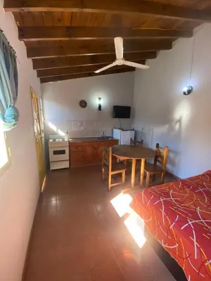 a bedroom with a bed and a table and a kitchen at Departamentos Altos del Puchuqui in Santa Rosa de Calamuchita