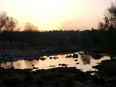 a sunset over a river with rocks in it at El Remanso in Villa Independencia