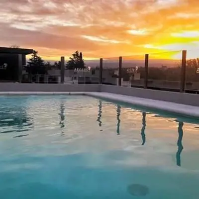 a large swimming pool with a sunset in the background at ARECAS Carlos Paz in Villa Carlos Paz