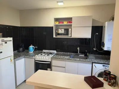 a kitchen with white cabinets and a stove top oven at ARECAS Carlos Paz in Villa Carlos Paz