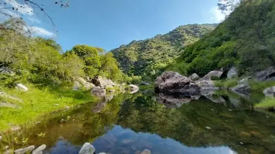 a reflection of a mountain in a body of water at Cabañas MACONDO in Villa Ciudad Parque