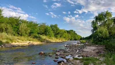 a river with rocks and trees on the side at Cabañas MACONDO in Villa Ciudad Parque
