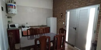 a kitchen with a table and chairs and a refrigerator at Cabañas MACONDO in Villa Ciudad Parque