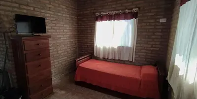 a small bedroom with a red bed and a window at Cabañas MACONDO in Villa Ciudad Parque