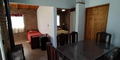 a dining room with a table and a bedroom at Cabañas MACONDO in Villa Ciudad Parque