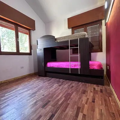 a bedroom with two bunk beds and a wooden floor at Amplia casa a solo unos metros del centro - RentVGB in Villa General Belgrano