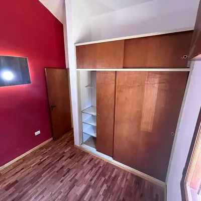 a closet with wooden cabinets and a red wall at Amplia casa a solo unos metros del centro - RentVGB in Villa General Belgrano