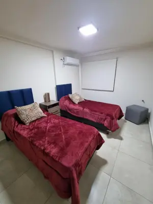 a room with two beds with red sheets and a white wall at Depto triplex frente el lago in Villa Carlos Paz