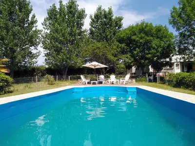 a blue swimming pool with an umbrella and chairs at Casa con vista al lago en Potrero de Garay in La Estancia