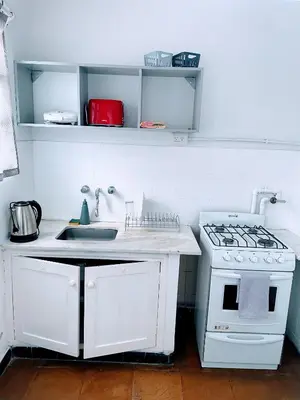 a white kitchen with a stove and a sink at Departamento de Santa Rosa in Cordoba