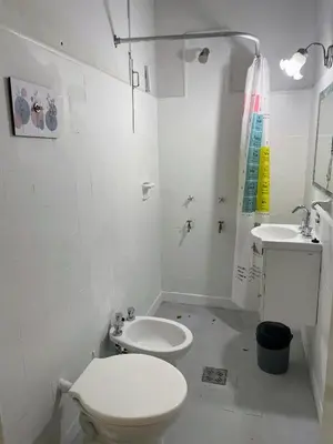 a white bathroom with a toilet and a sink at Departamento de Santa Rosa in Cordoba