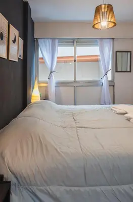 a bedroom with a large white bed with a window at Trejo 351 in Cordoba