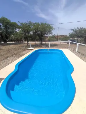 a large blue swimming pool in a yard at Departamentos Atardecer Serrano in Arroyo de Los Patos