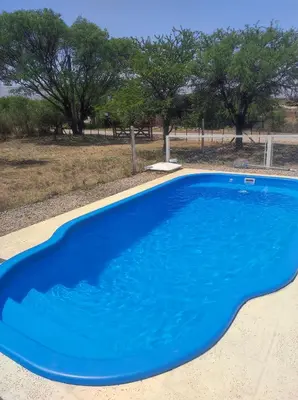 a blue swimming pool with trees in the background at Departamentos Atardecer Serrano in Arroyo de Los Patos