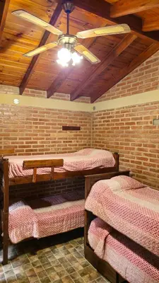 a room with three beds and a ceiling fan at Departamentos Atardecer Serrano in Arroyo de Los Patos