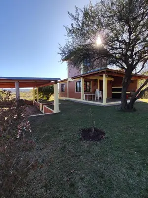 a house with a tree in the yard at Departamentos Atardecer Serrano in Arroyo de Los Patos