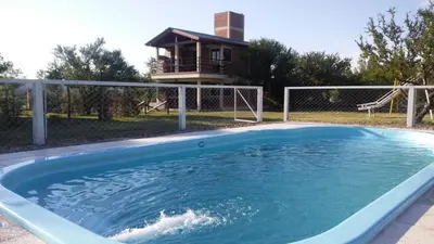 a large swimming pool with a house in the background at Departamentos Atardecer Serrano in Arroyo de Los Patos