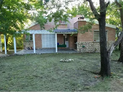 a house with three dogs laying in the yard at Cabaña La Lechuza en LAS RABONAS in Mina Clavero