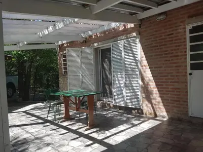 a patio with a table and a window with shutters at Cabaña La Lechuza en LAS RABONAS in Mina Clavero